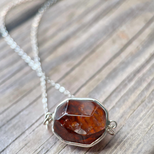 Necklace with a deep red Hematoid pendant on a wooden surface