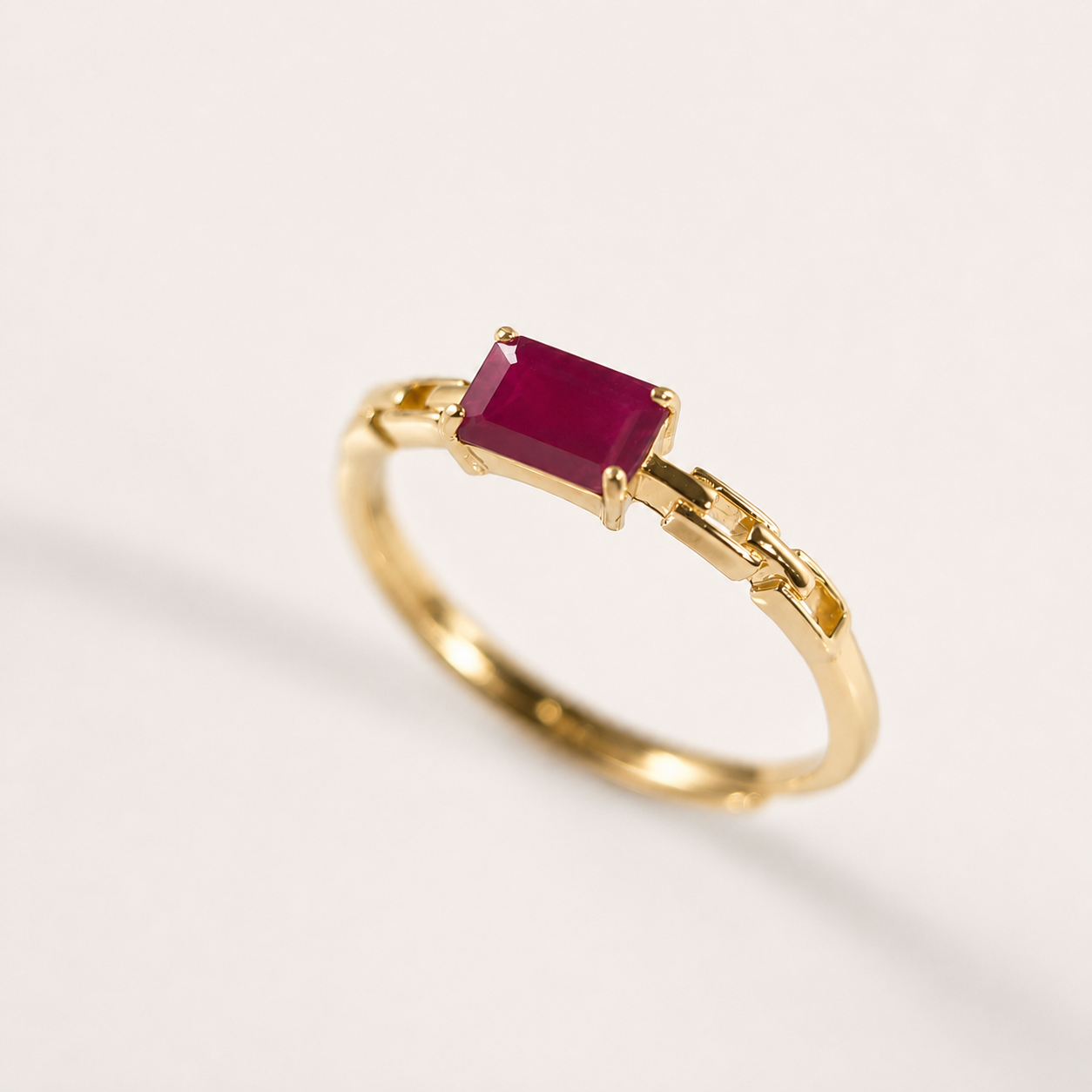 A gold ring featuring a rectangular ruby, photographed on a clean white background.