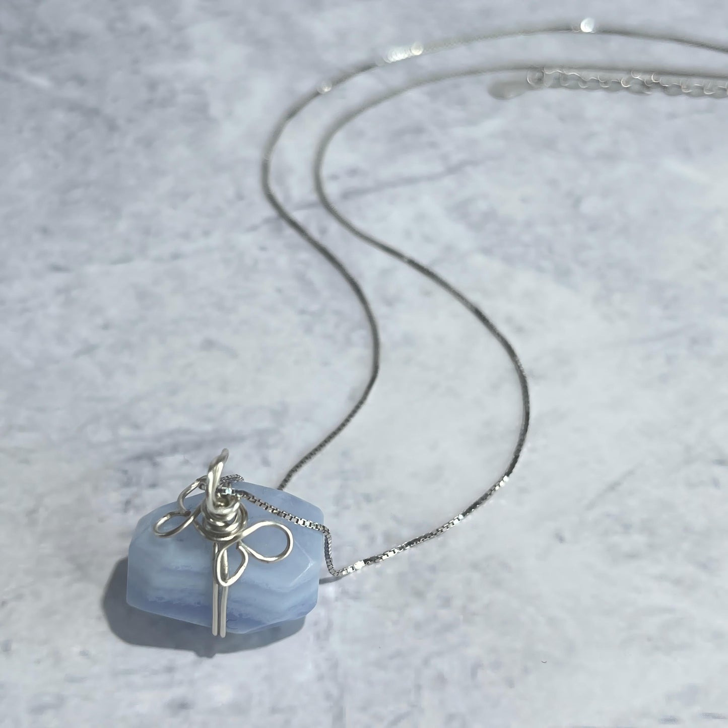 Necklace with a blue pendant on a textured gray surface