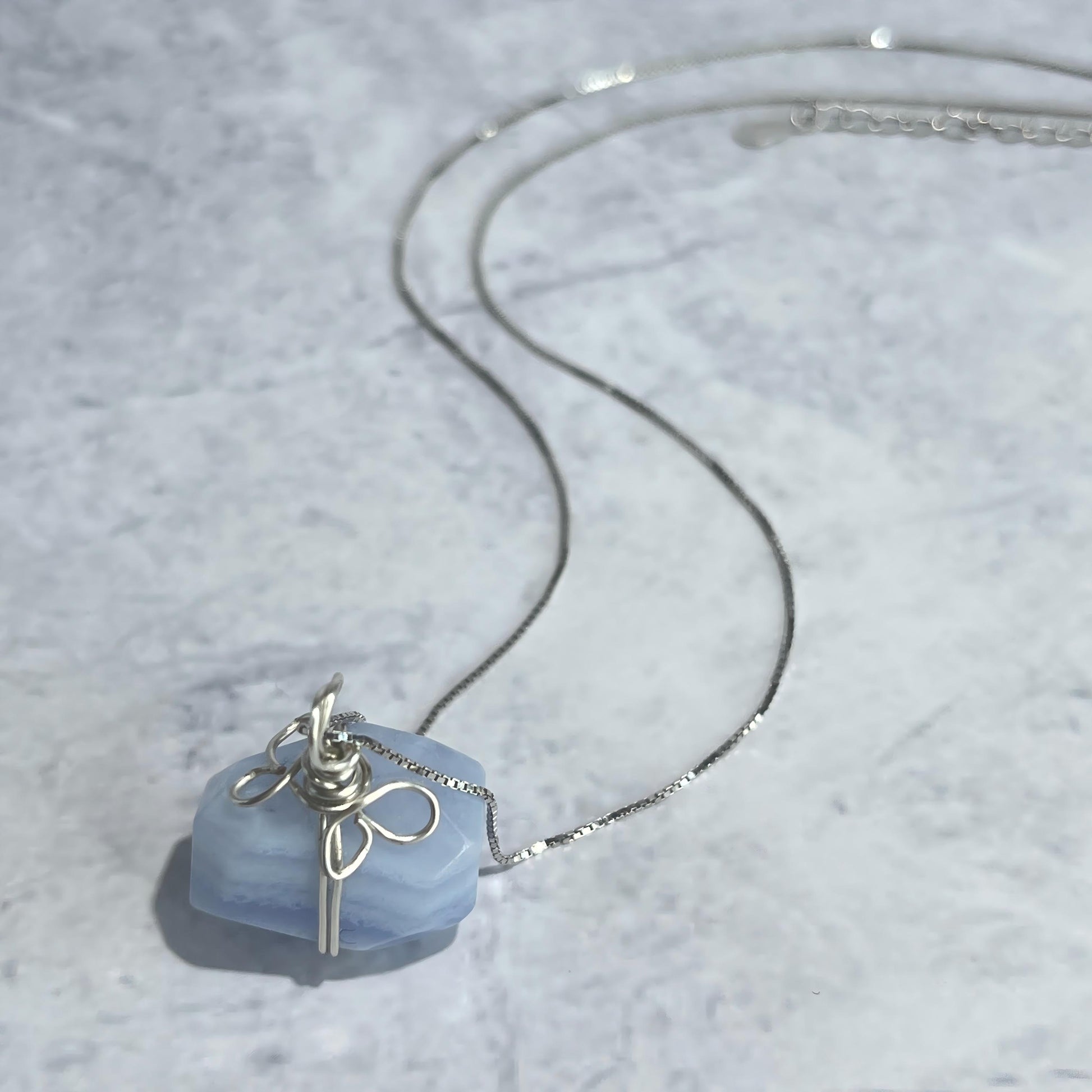 Necklace with a blue pendant on a textured gray surface