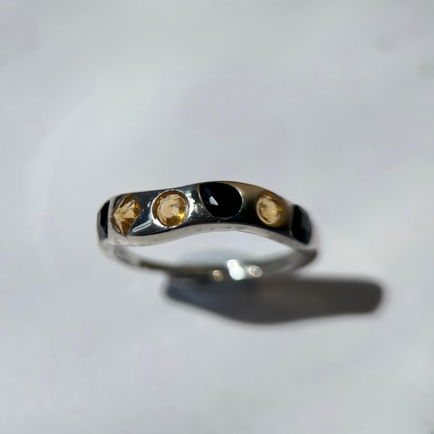 Silver ring with embedded stones on a light gray background