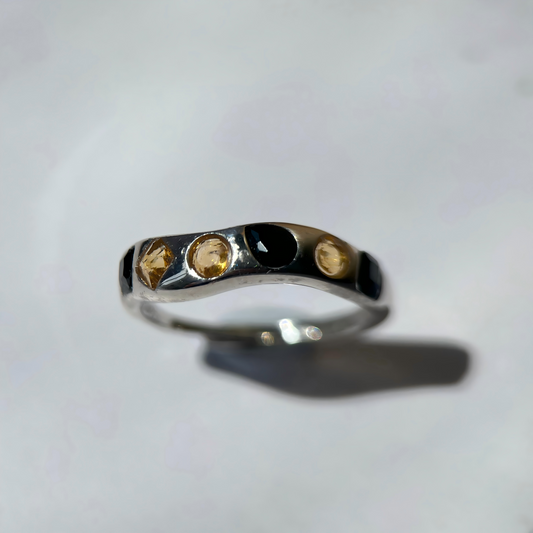 Silver ring with embedded stones on a light gray background