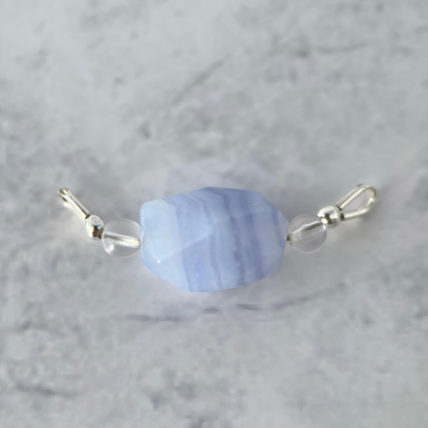 Blue lace agate bead with silver accents on a gray background