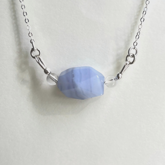Necklace with a blue faceted bead on a white background