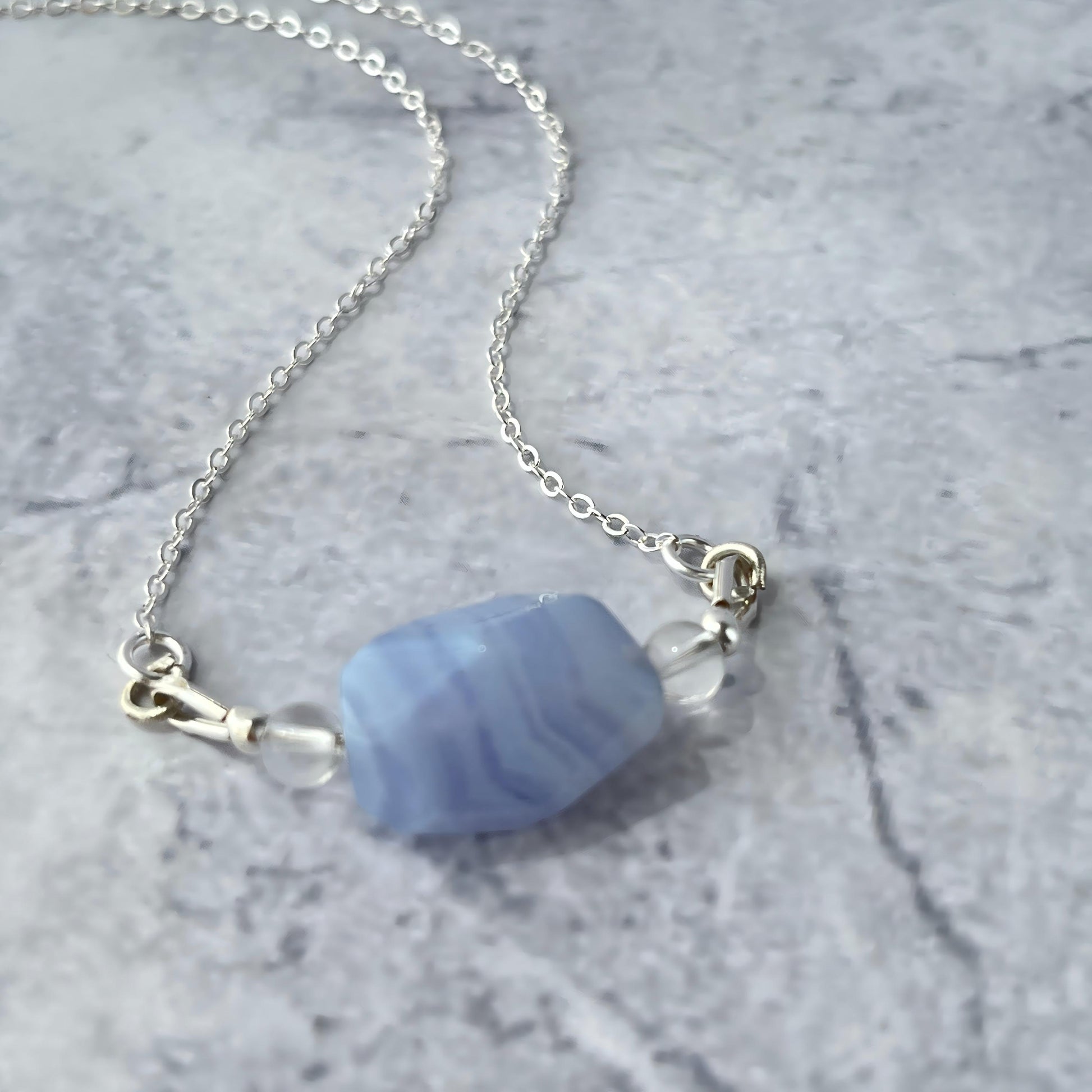 Necklace with a blue stone pendant on a marble surface