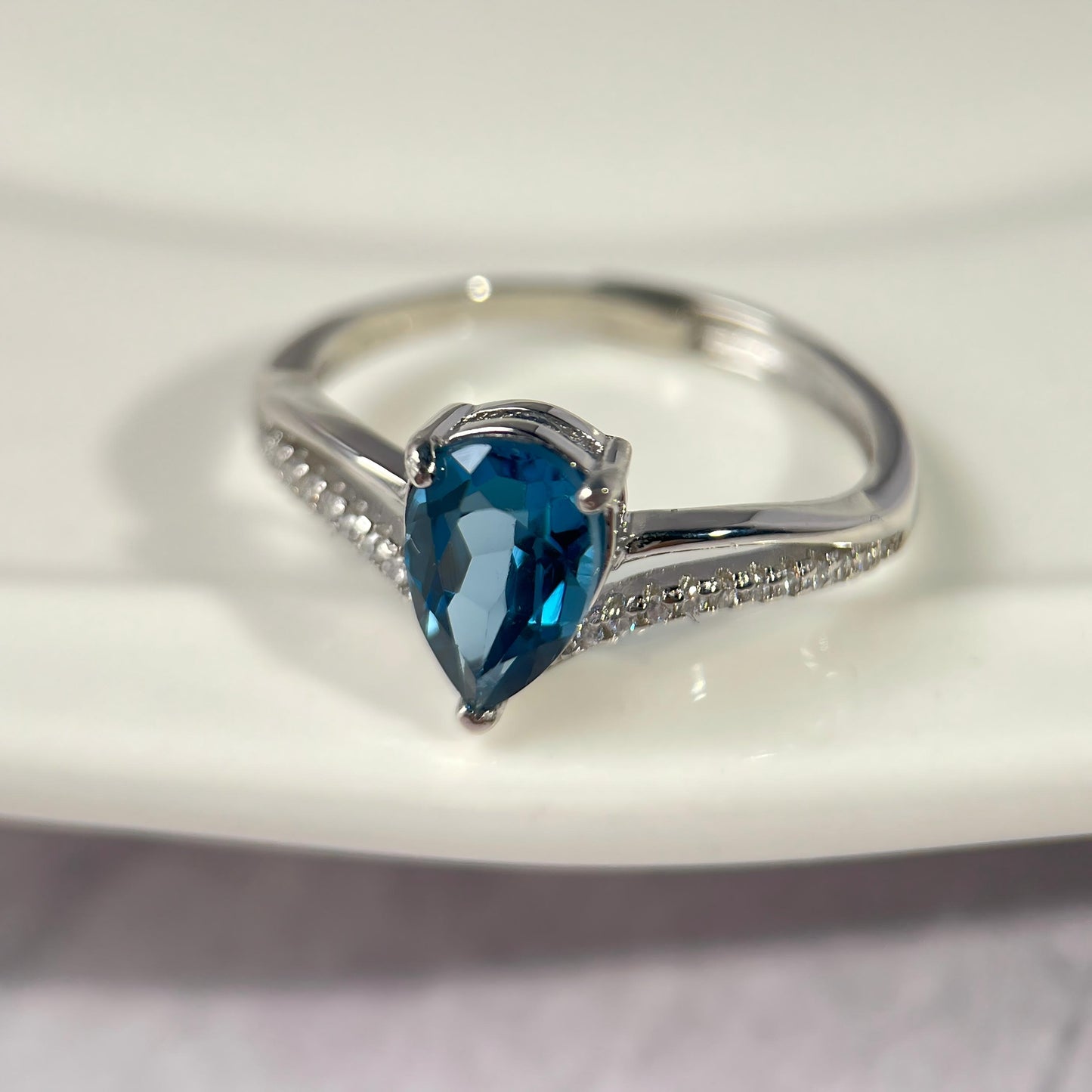 Silver ring with a blue gemstone on a white background