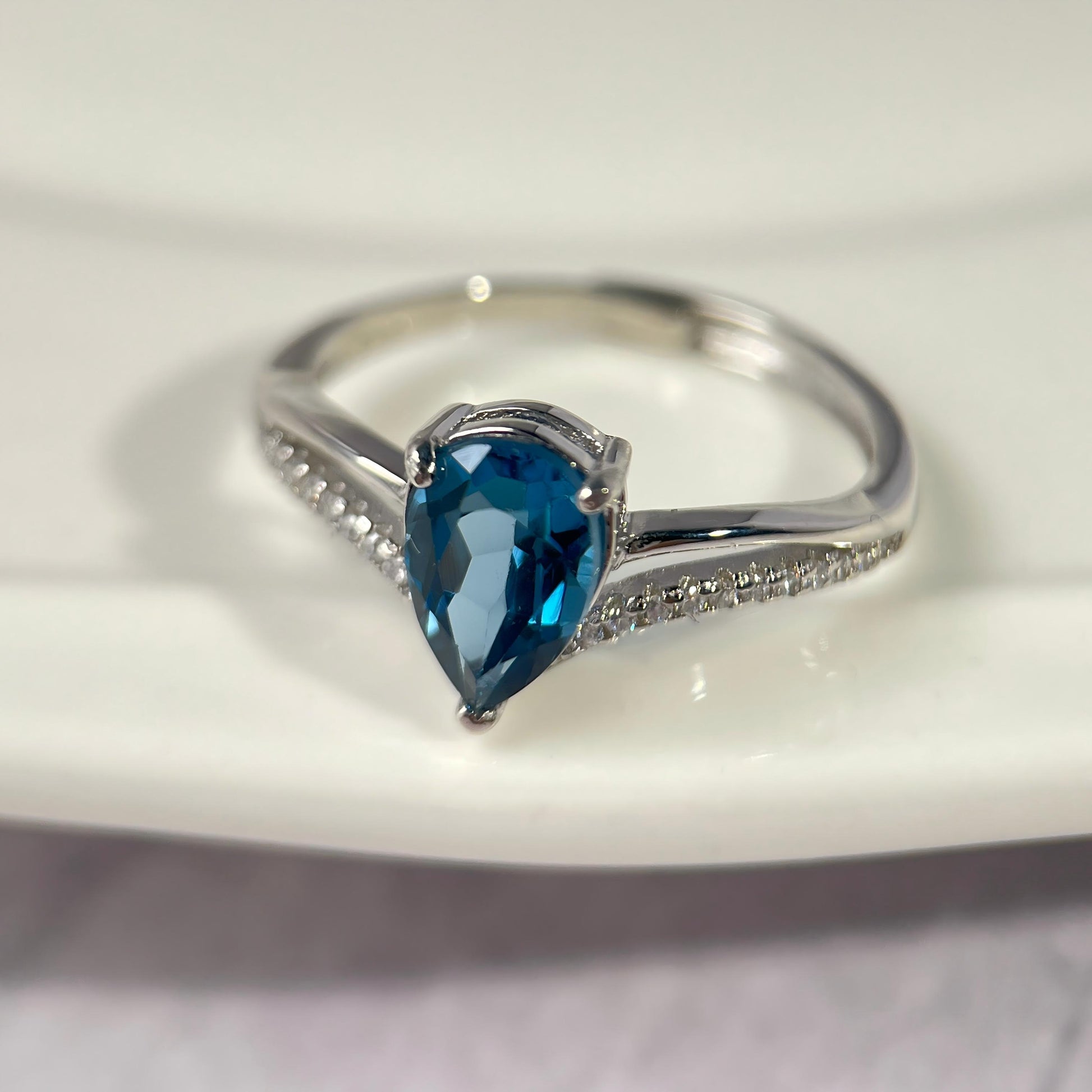 Silver ring with a blue gemstone on a white background