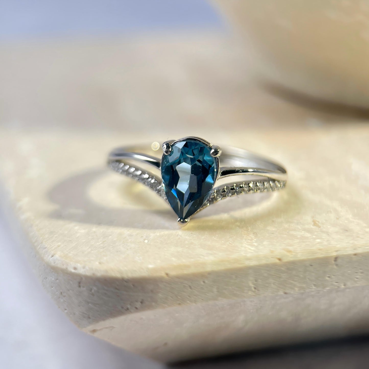 Silver ring with a blue gemstone on a marble surface
