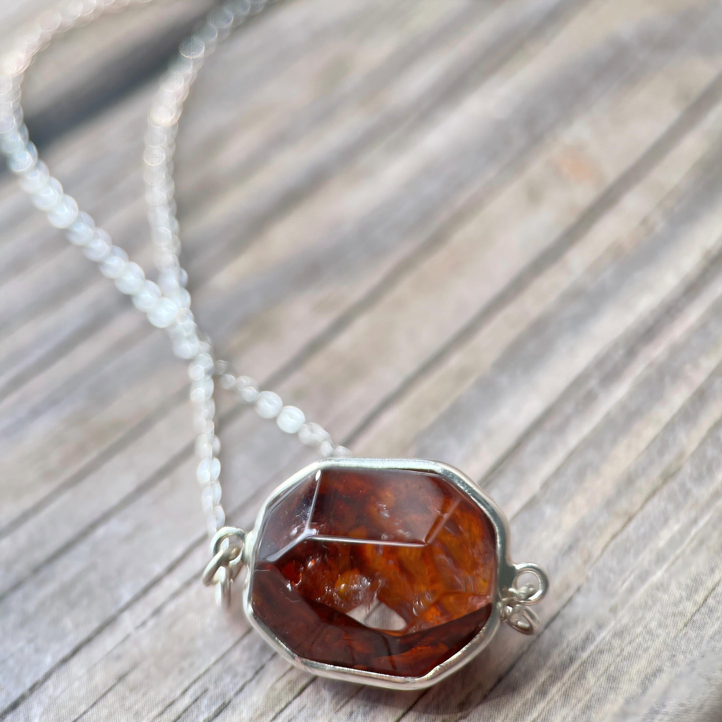 Necklace with a deep red Hematoid pendant on a wooden surface