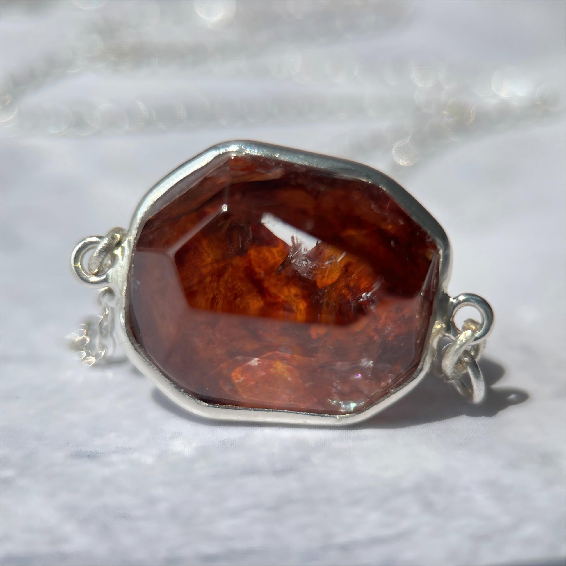Hematoid pendant with silver setting on a textured white background