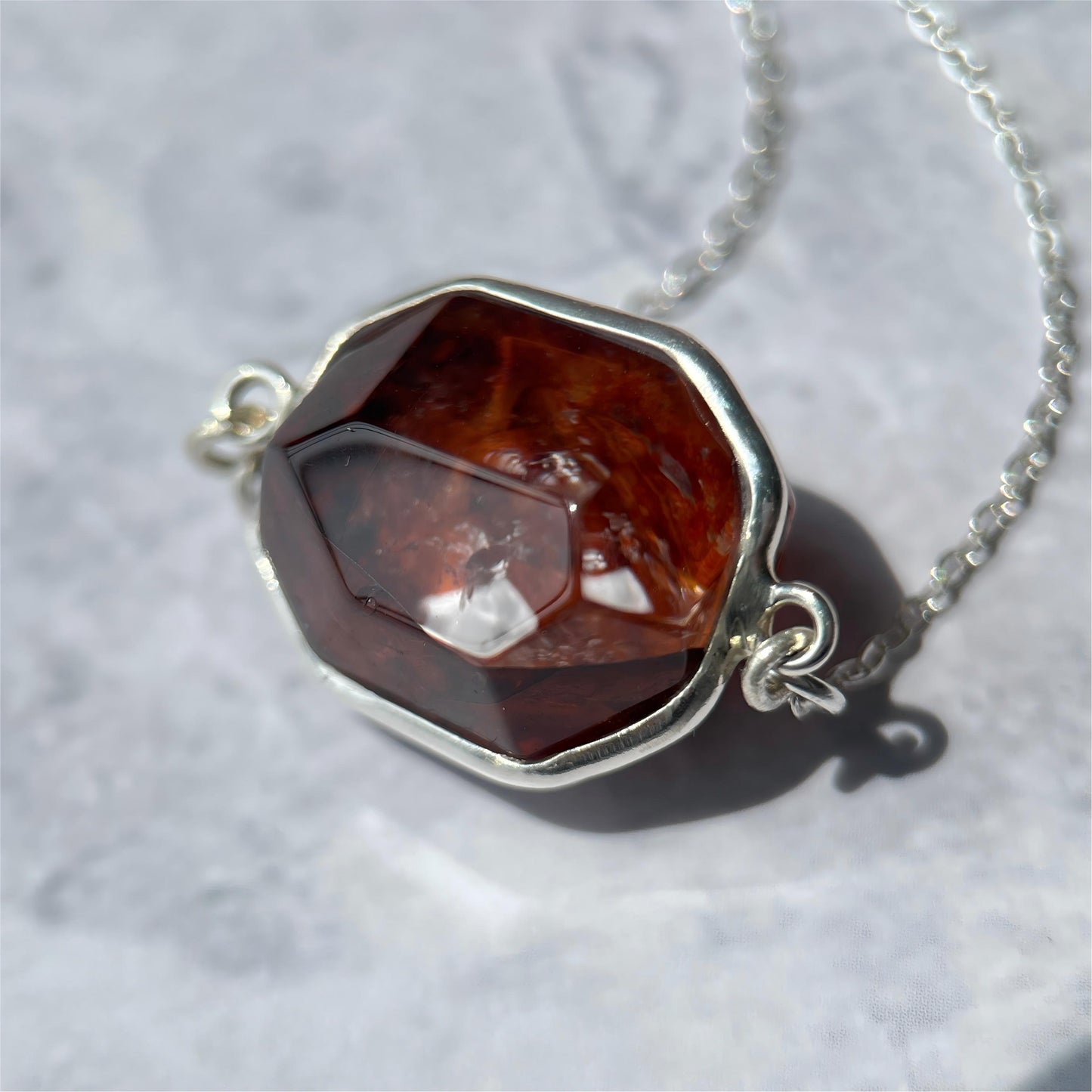 Necklace with a deep red Hematoid quartz pendant on a light gray background