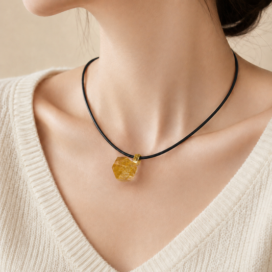Necklace with a polygonal yellow pendant worn by a person in a beige sweater.