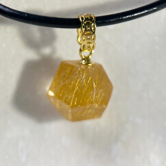 Gold Rutilated Quartz pendant on a black cord against a light background