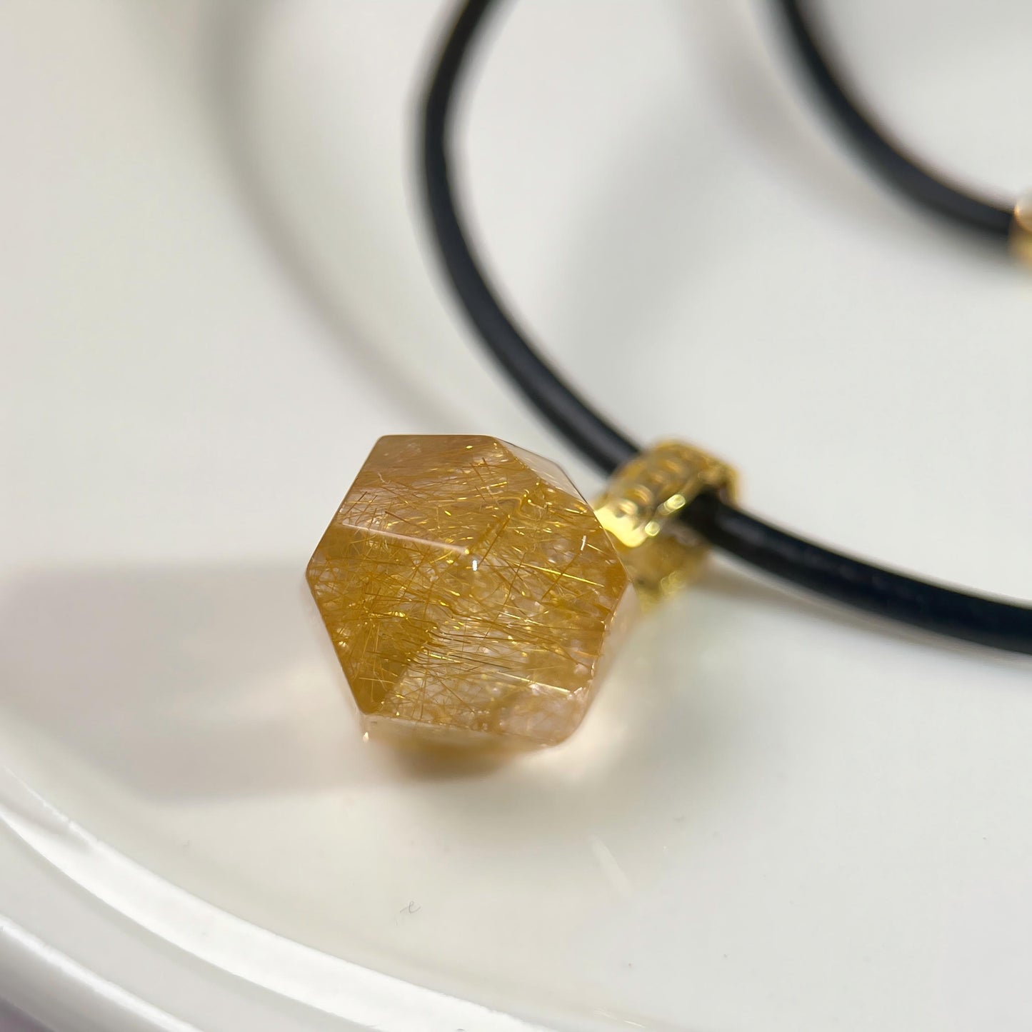 Necklace with a polygonal rutilated quartz pendant on a white background