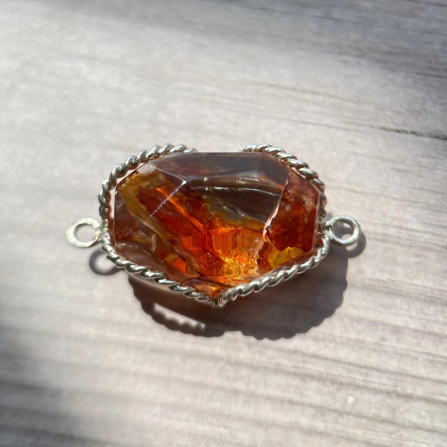 Jewelry clasp with amber-colored stone on a wooden surface