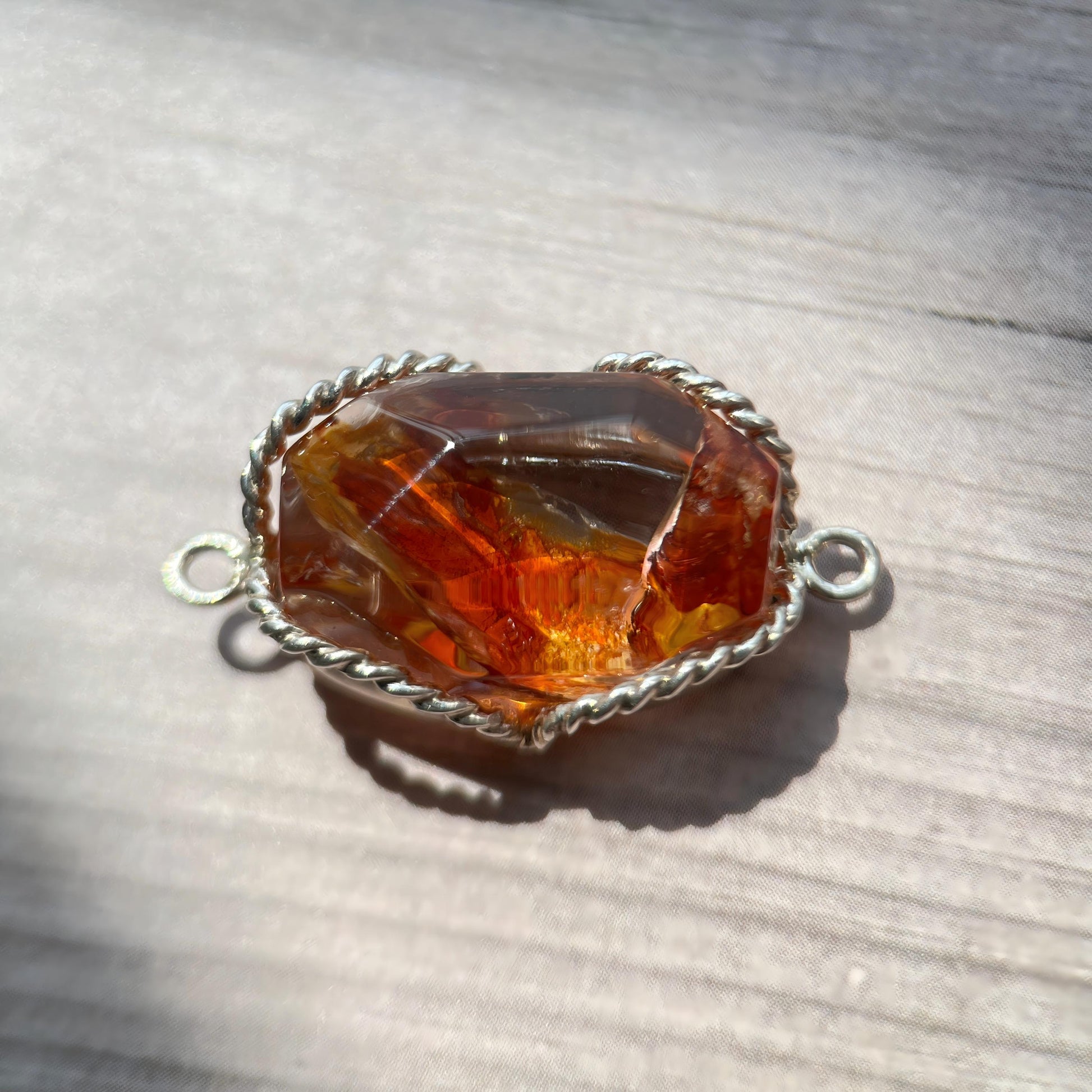 Jewelry clasp with amber-colored stone on a wooden surface