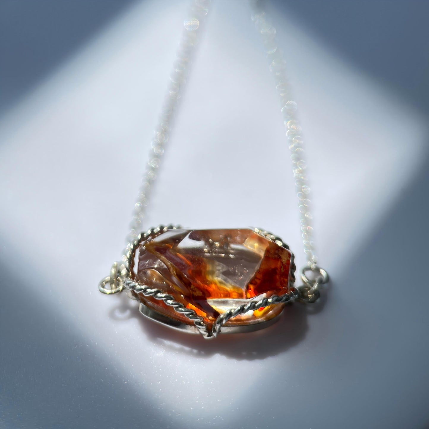 Necklace with a large amber-colored gemstone pendant on a light background