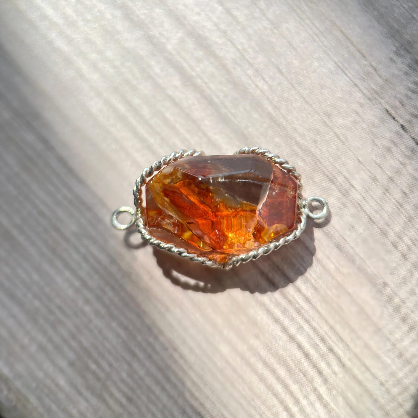 Amber stone pendant with silver setting on a wooden surface