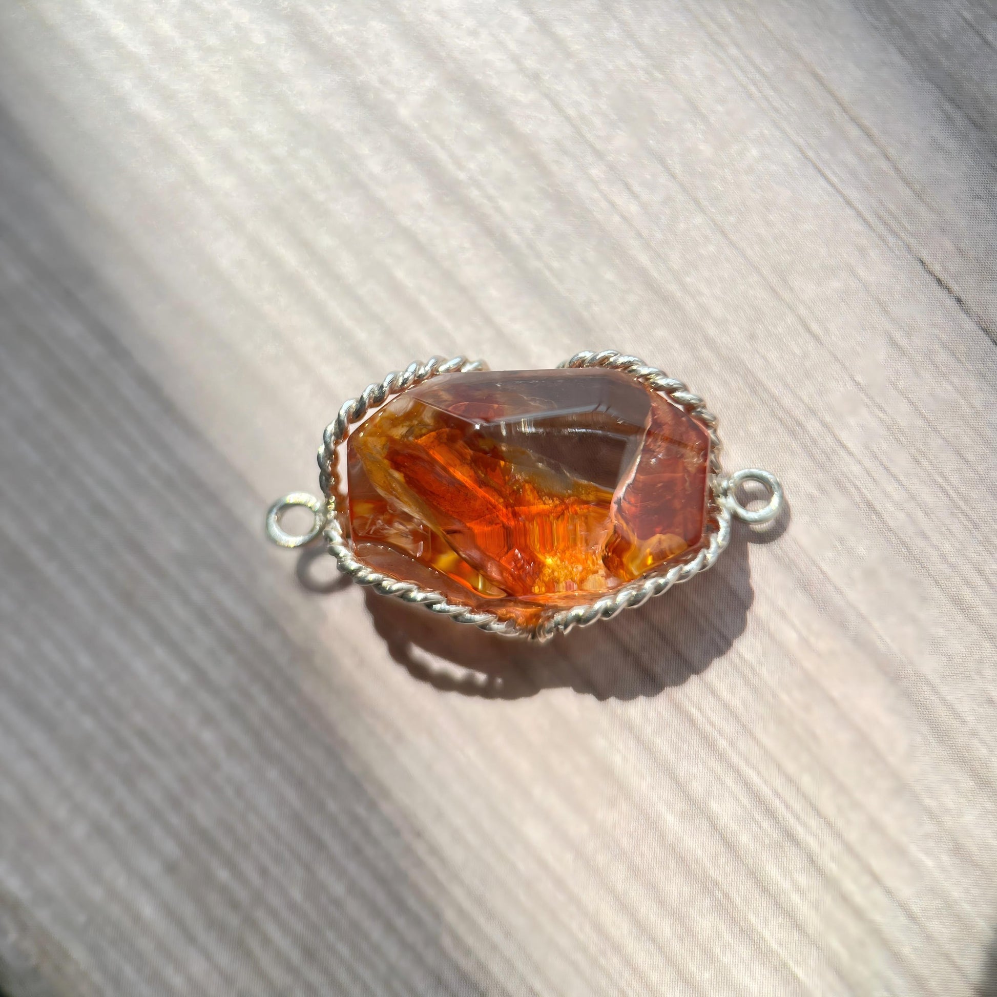 Amber stone pendant with silver setting on a wooden surface