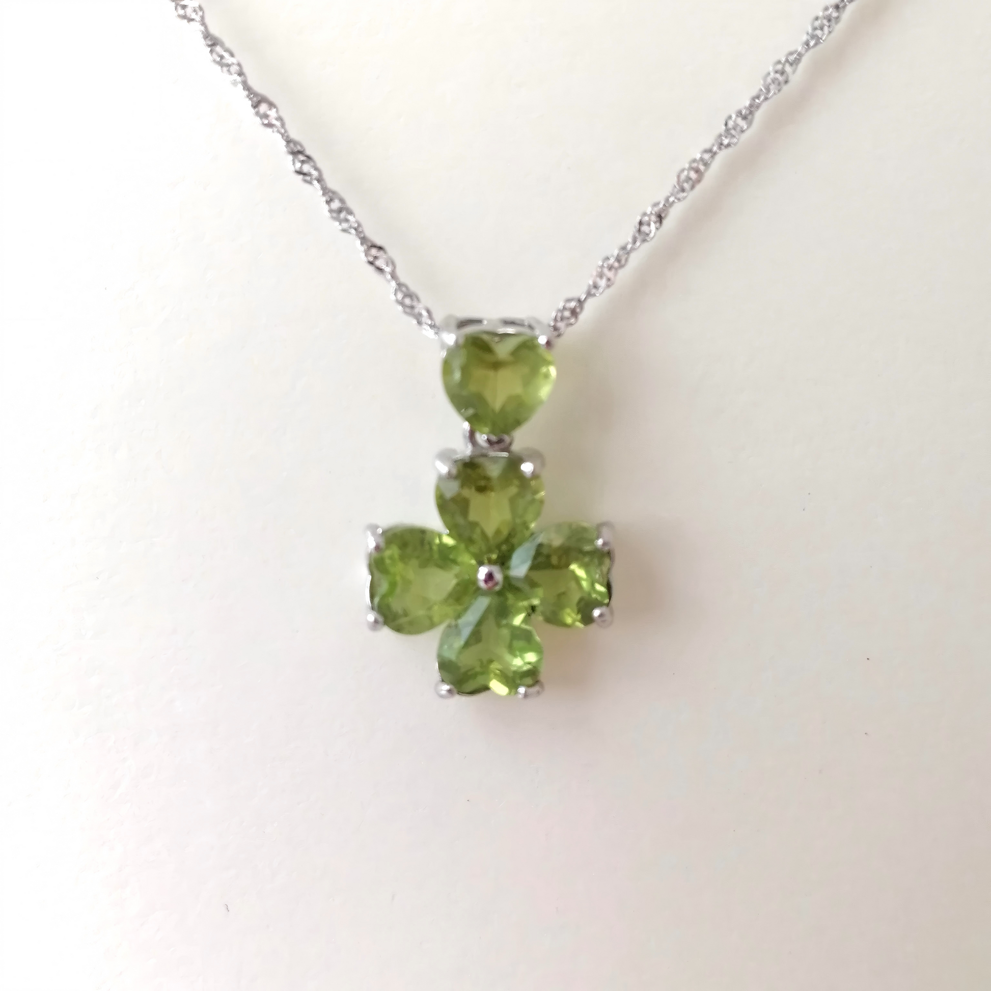 Green four-leaf clover pendant on a white background