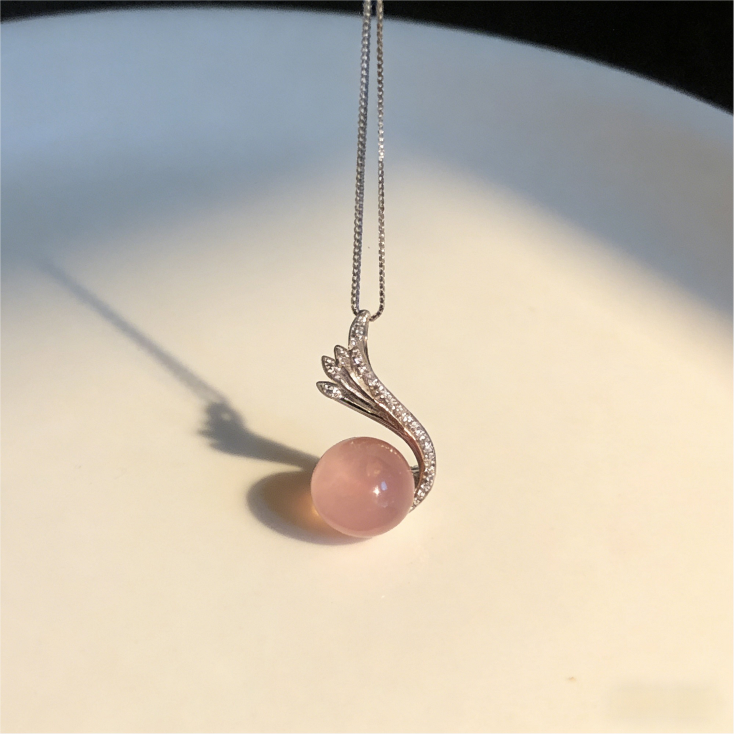 Pink gemstone necklace with silver chain on a light background