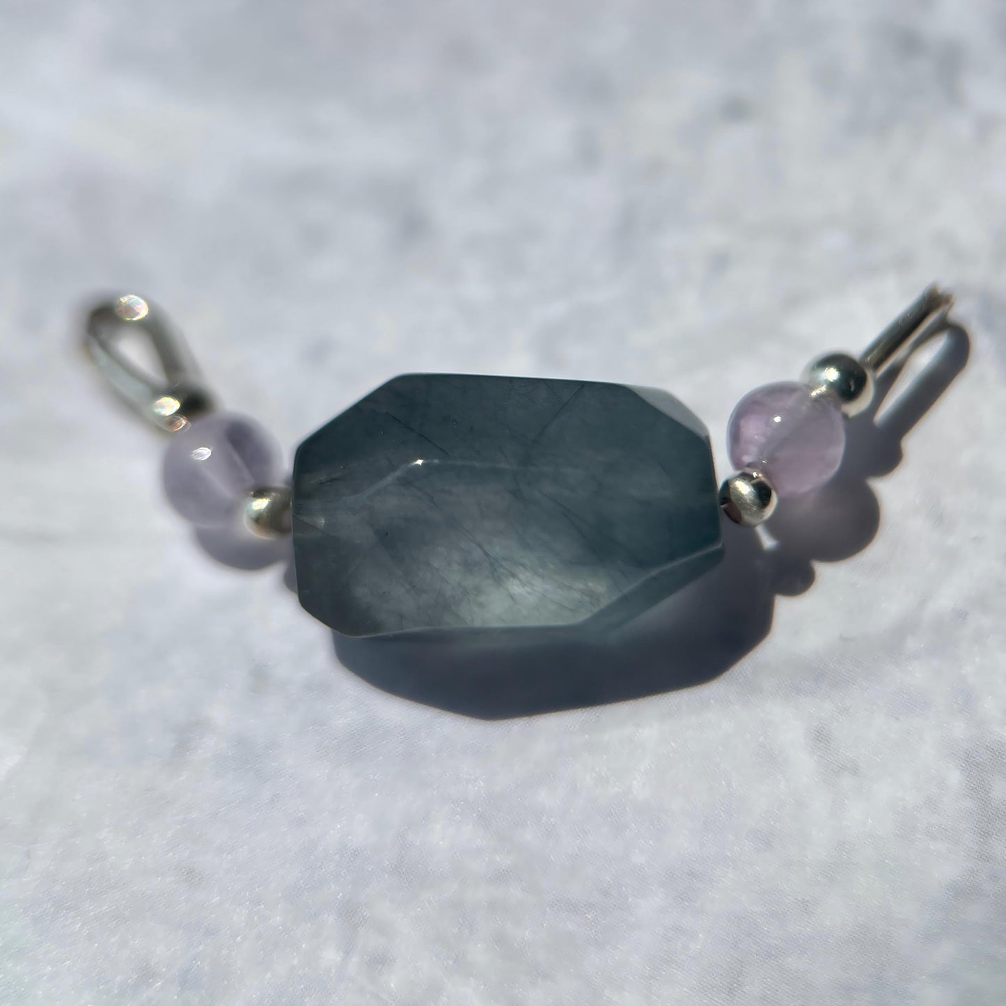 Bracelet with a large faceted stone and smaller beads on a white background