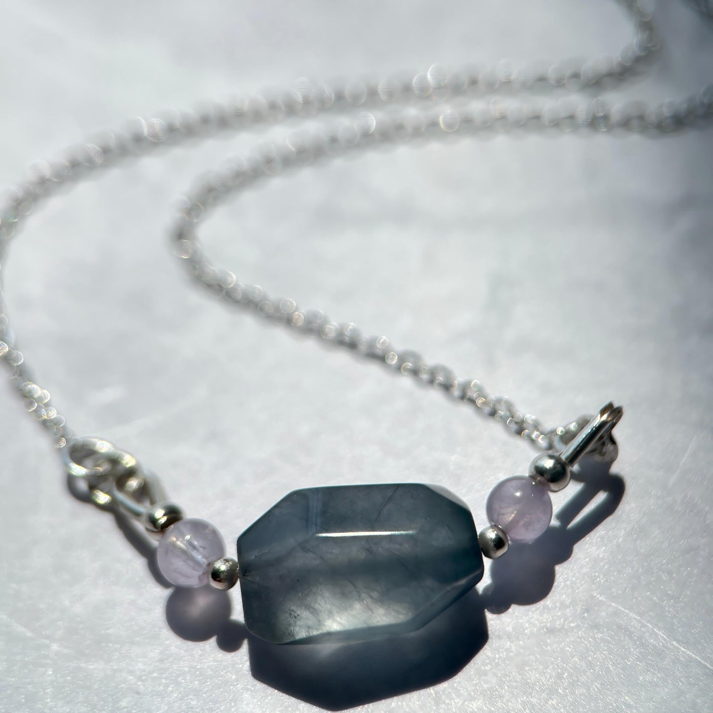 Necklace with a large hexagonal stone and smaller beads on a white background