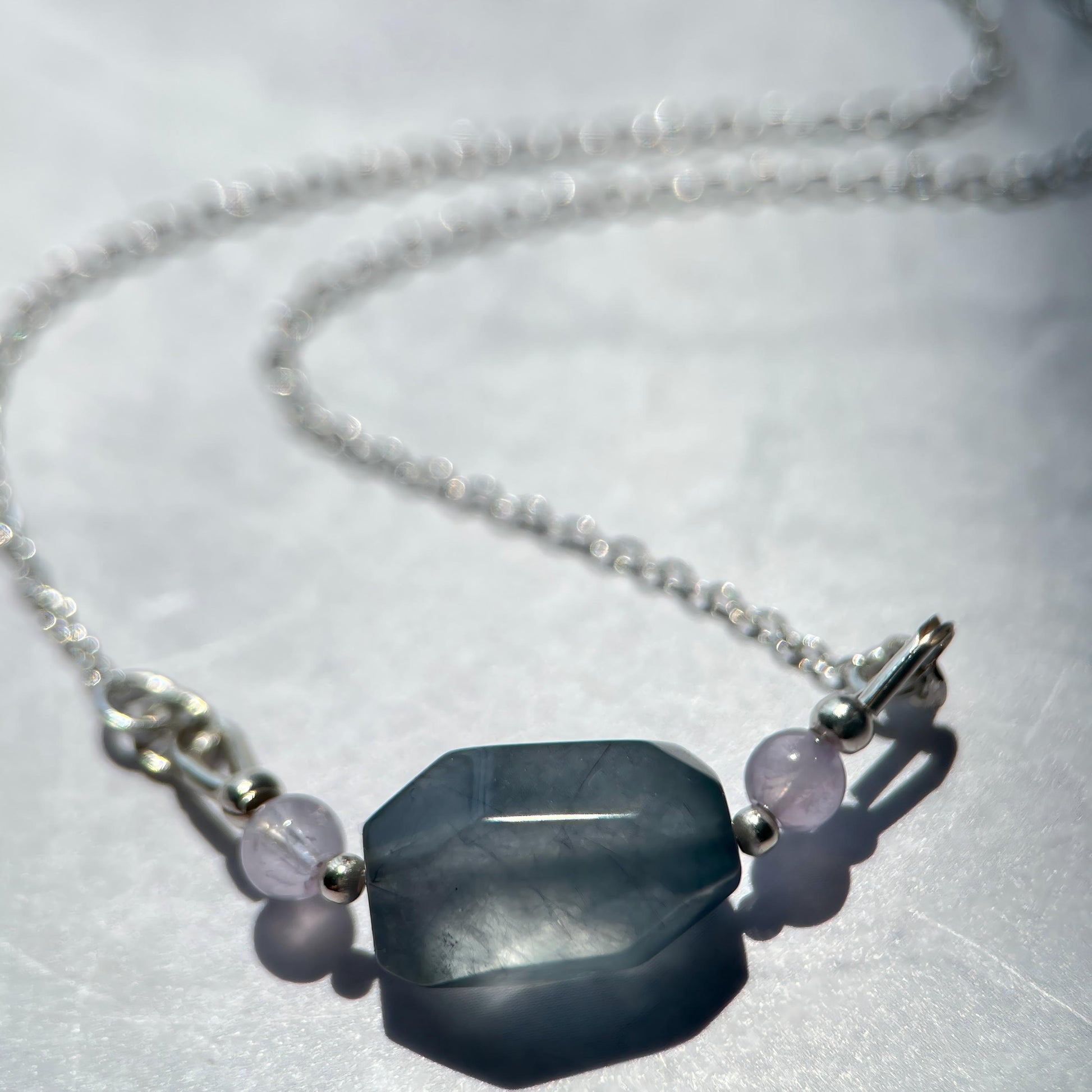 Necklace with a large hexagonal stone and smaller beads on a white background