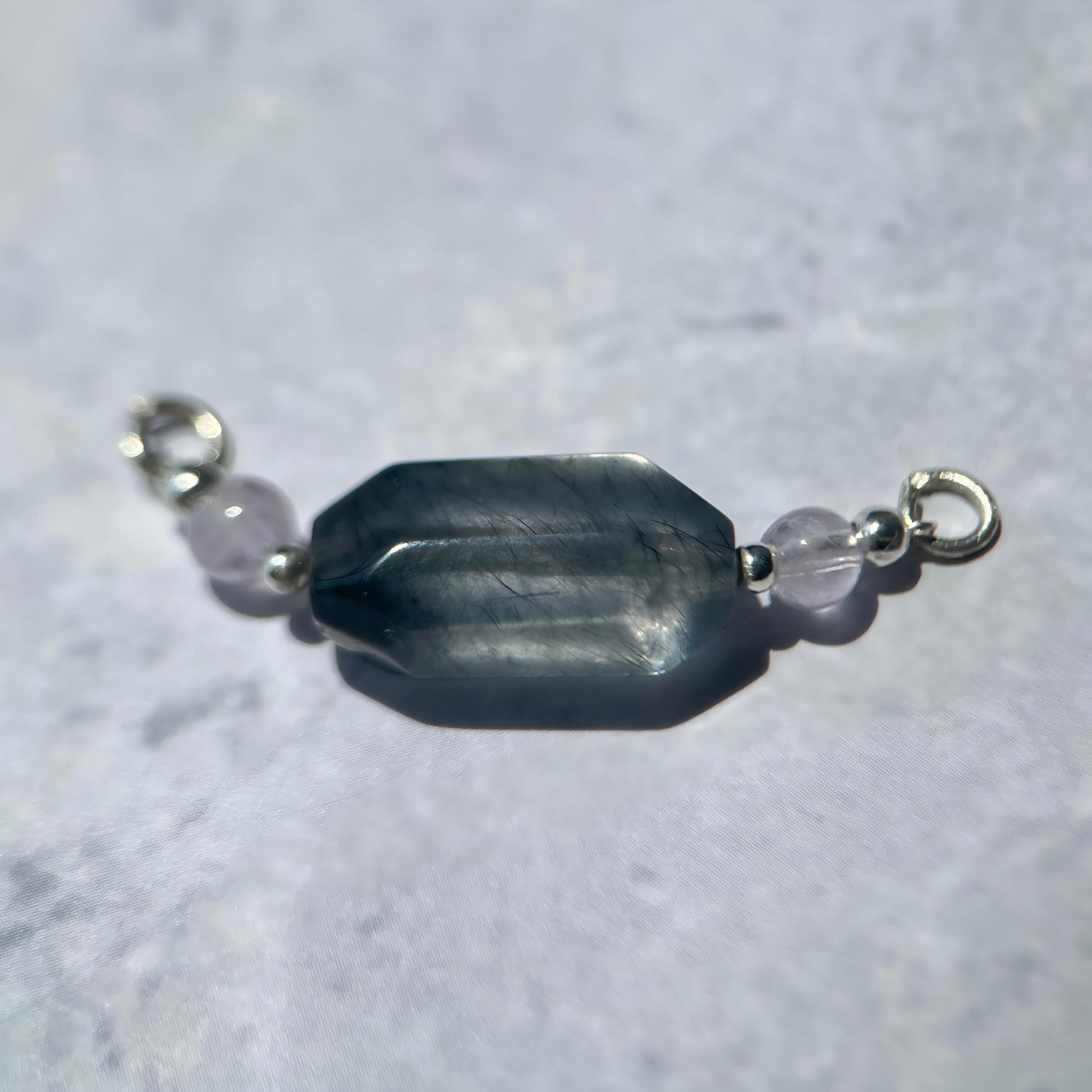 Pendant with a central blue stone and smaller clear stones on a light gray background