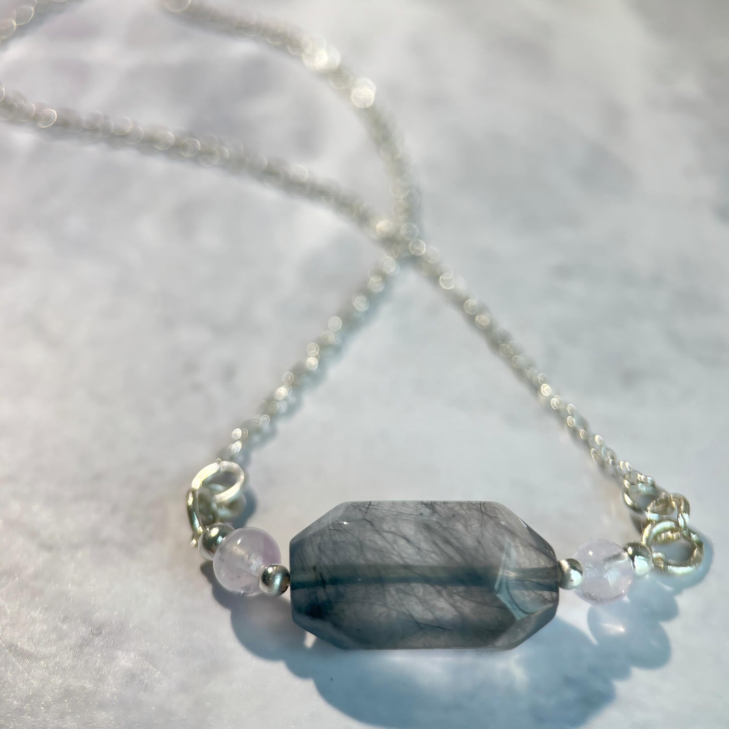 Necklace with a large blue stone and smaller beads on a light background