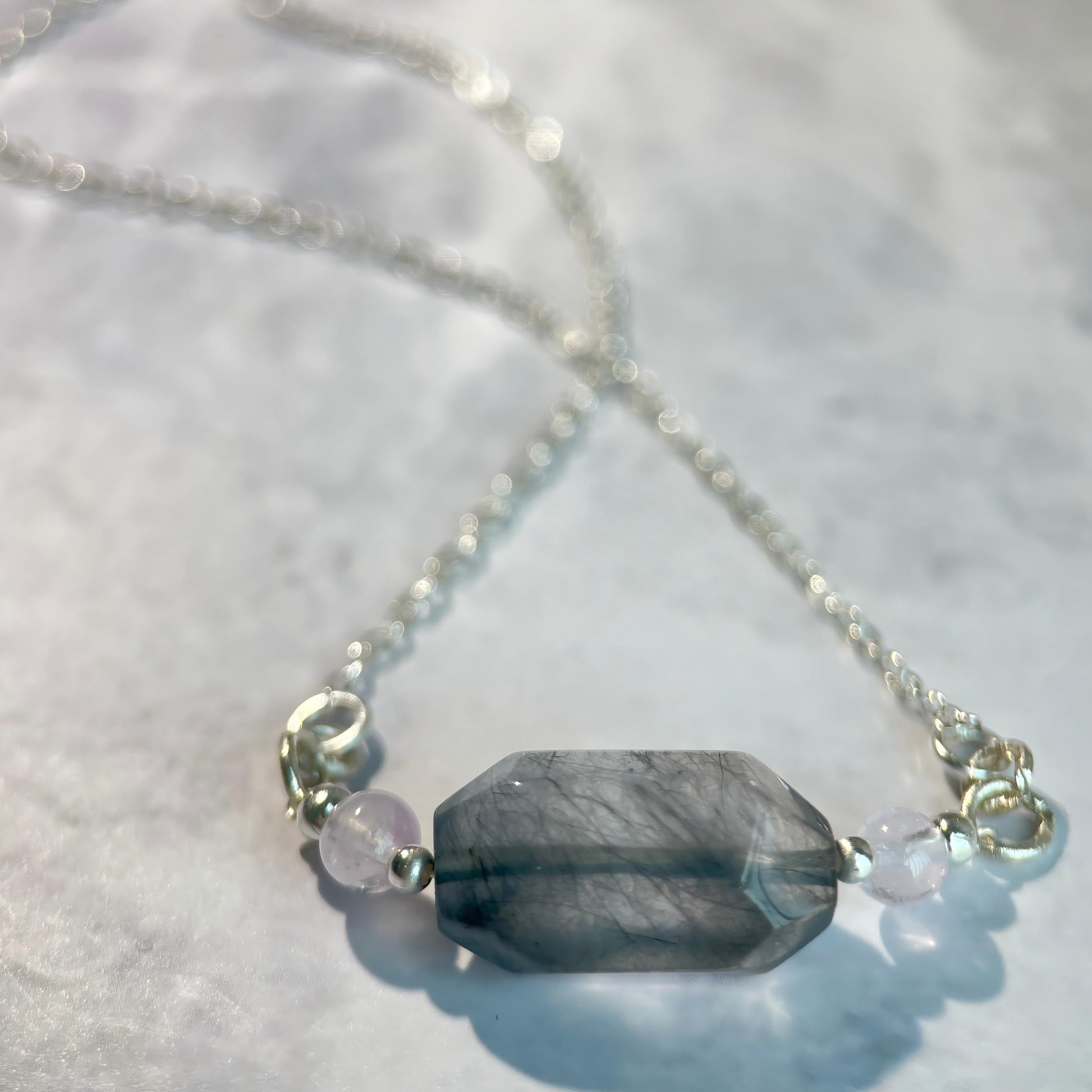 Necklace with a large blue stone and smaller beads on a light background